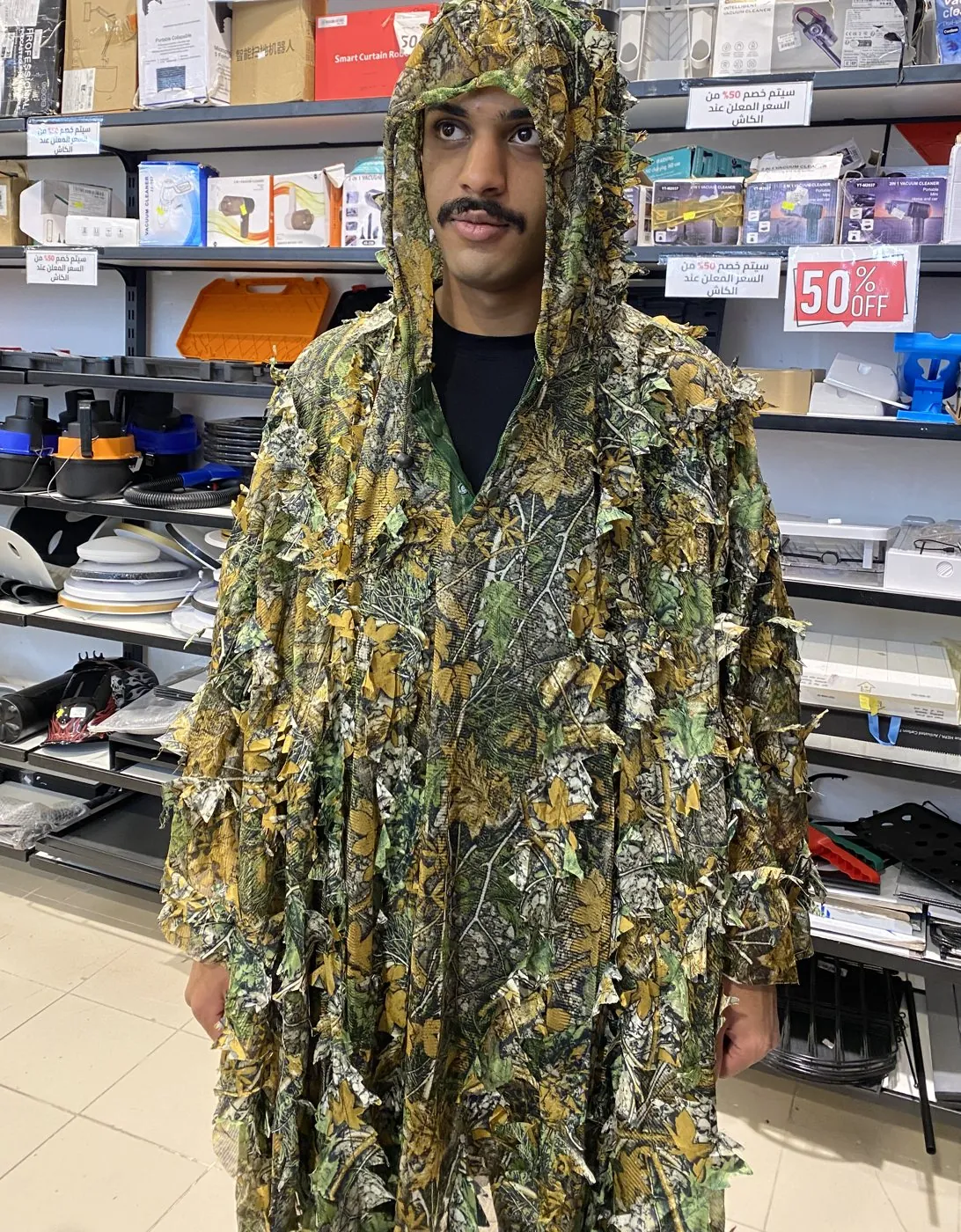 Ali wearing a leafy camouflage suit in a shop